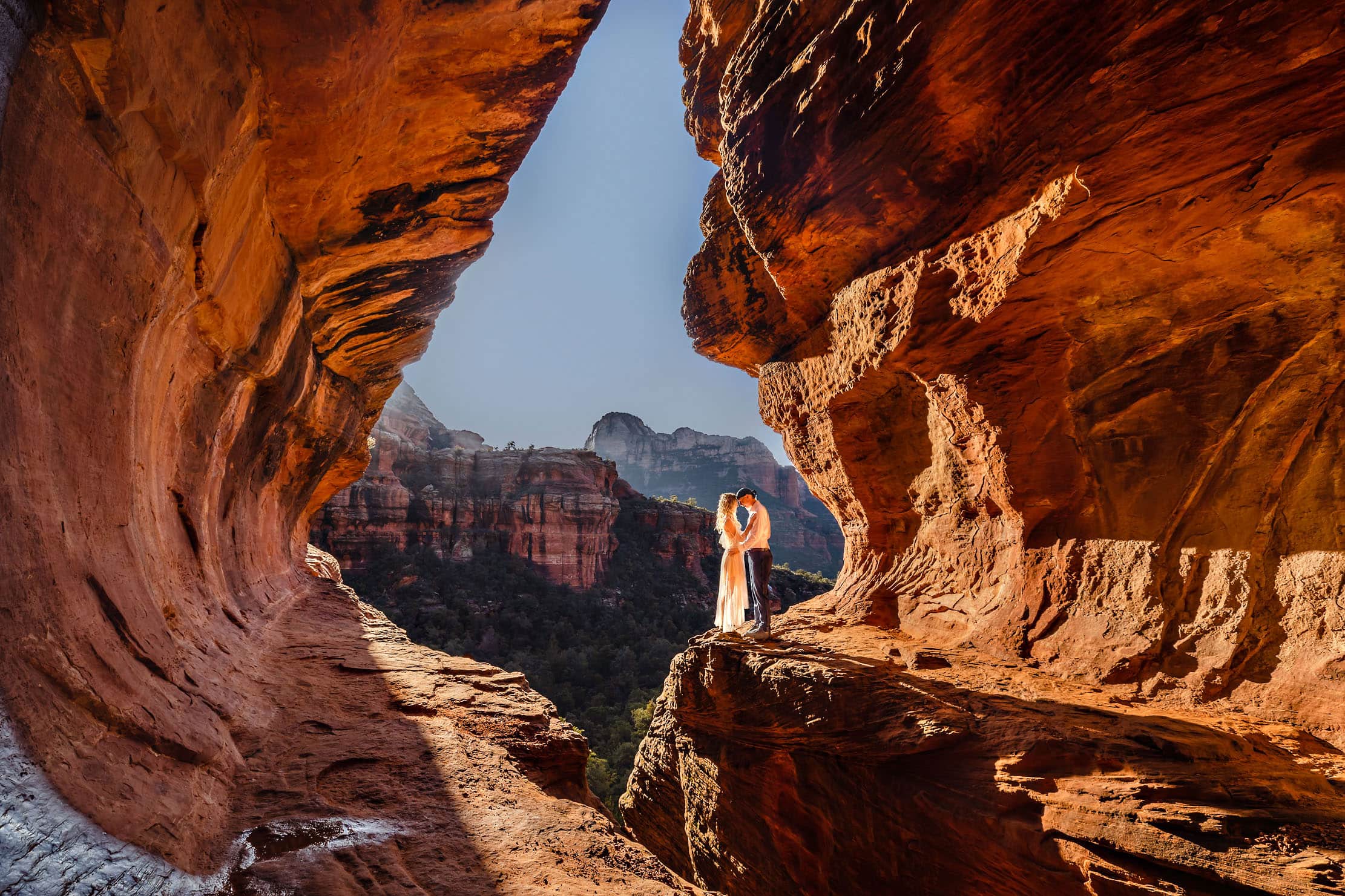 A wedding couple standing among the redrock enjoying the sunrise