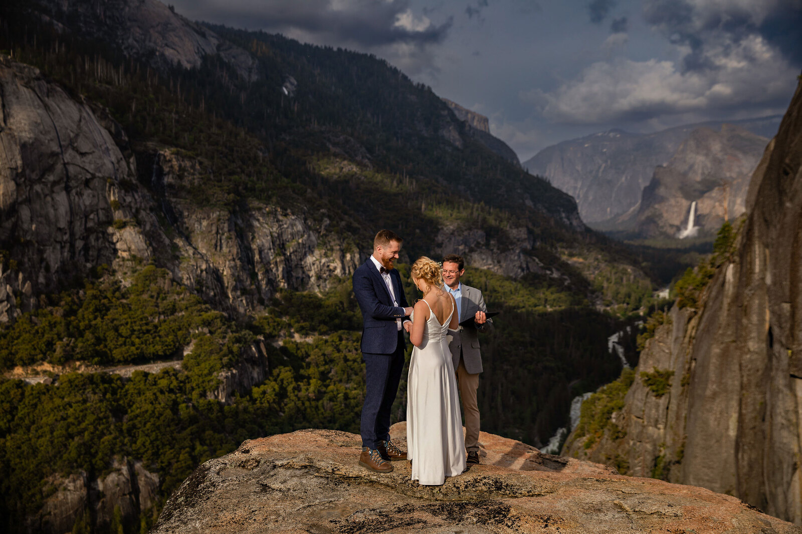 A Bride and Groom with the officiant having a wedding ceremony with mountains
