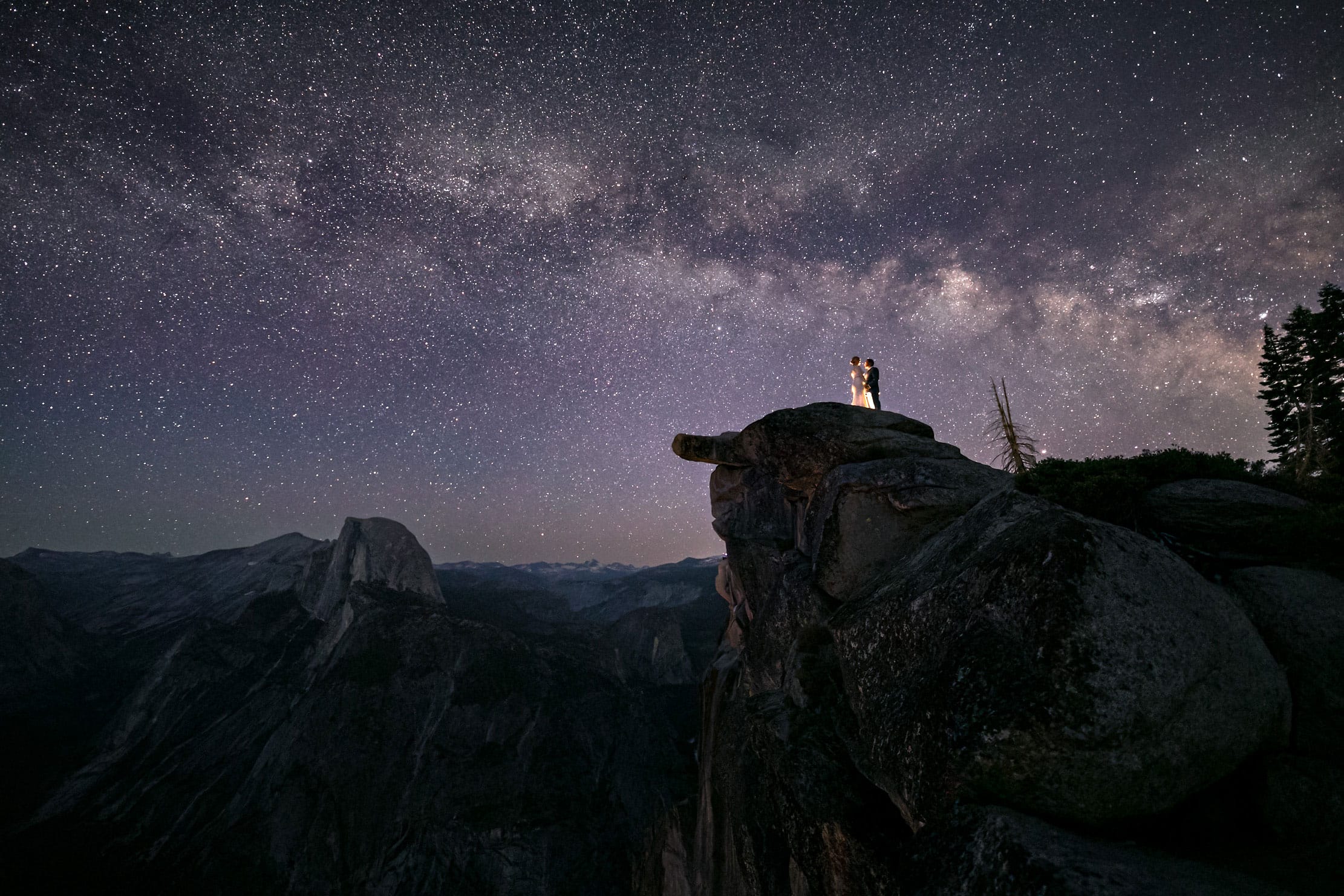 Wedding couple standing underneath the milky way with mountains at night