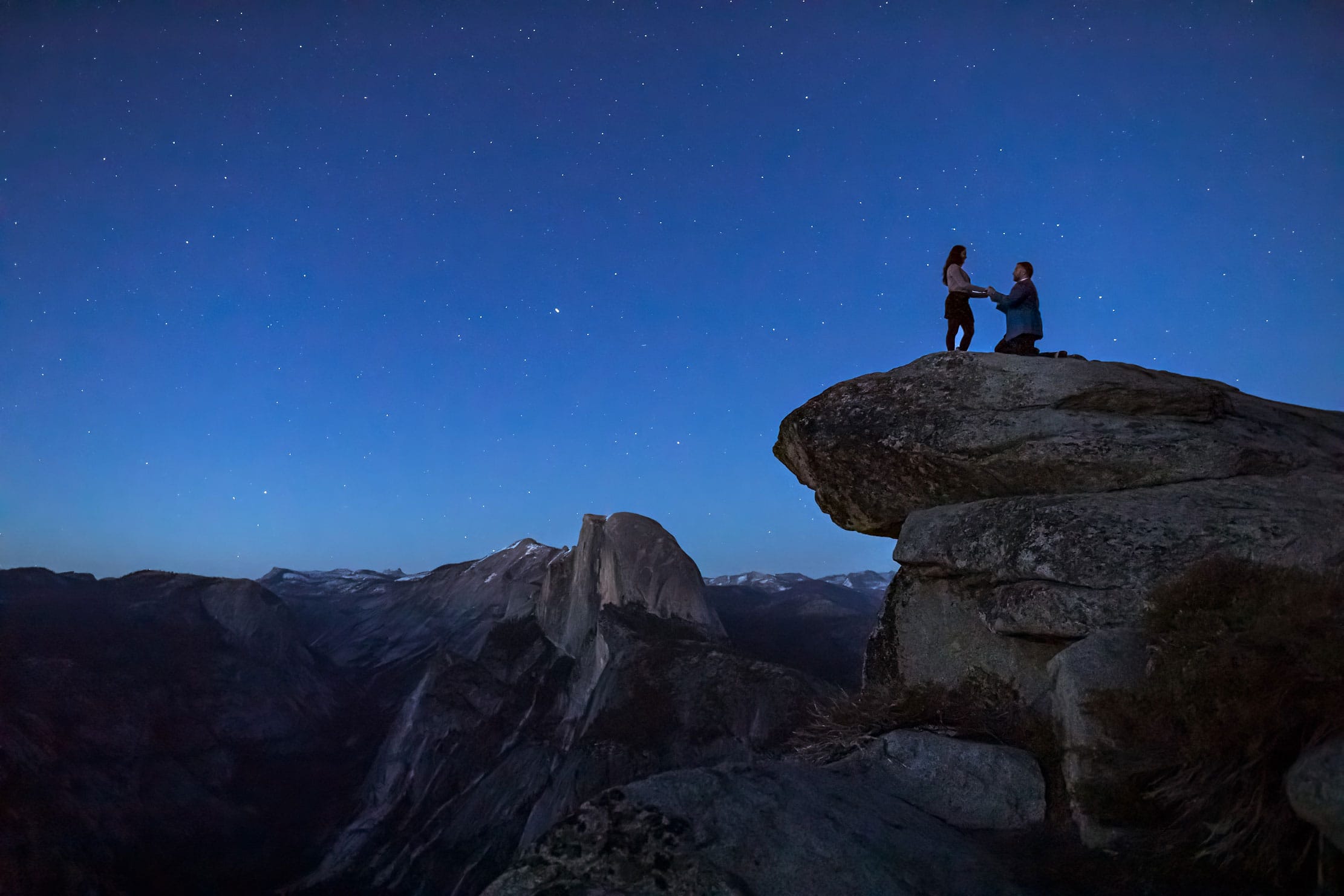 An engagement couple on top of mountain getting engaged.