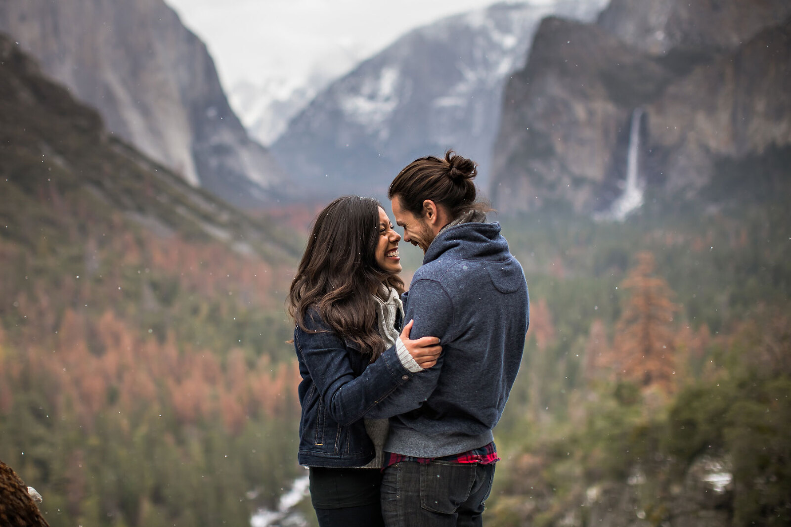 An engagement couple looking at each other laughing with mountains.