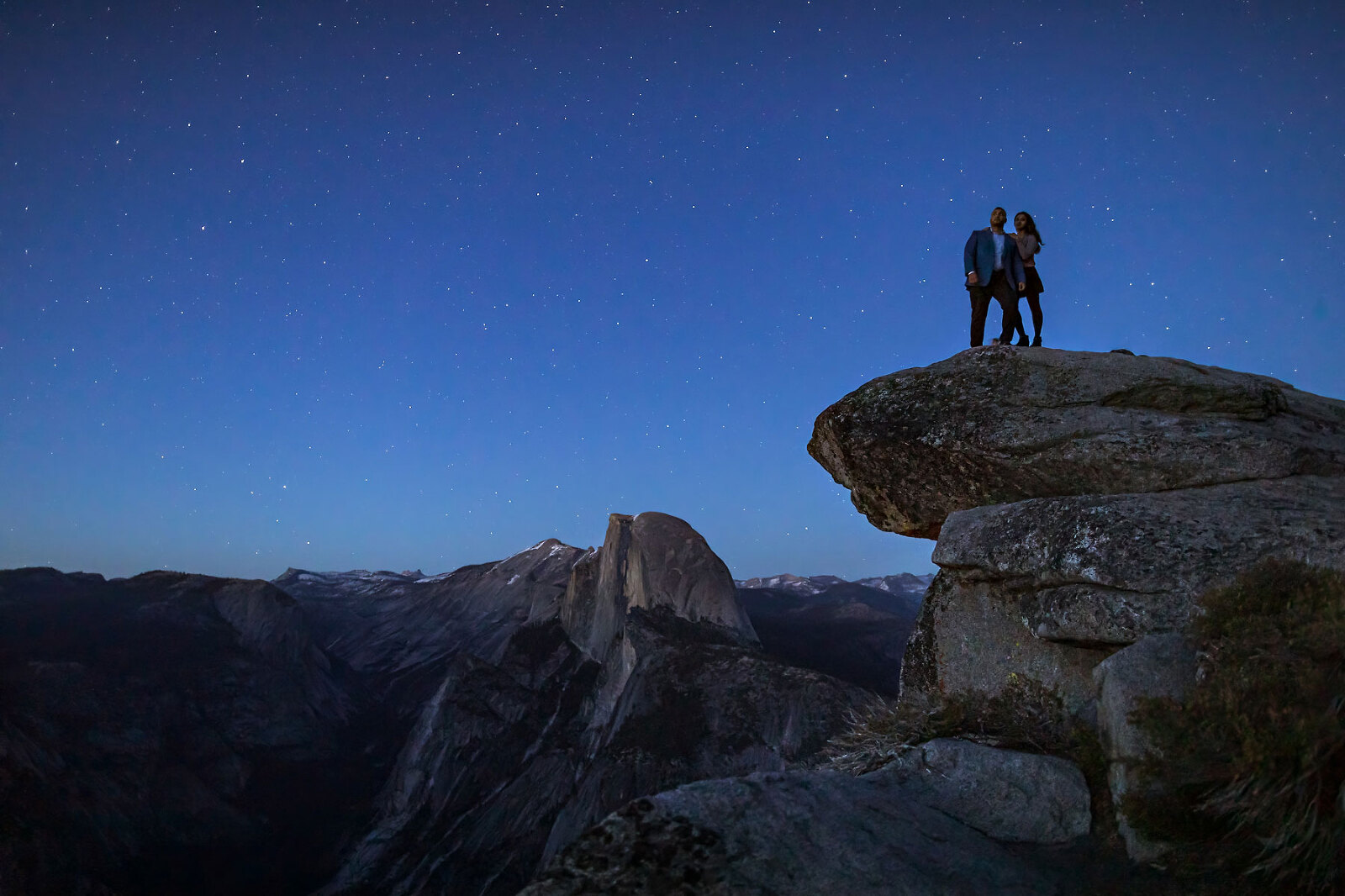 A couple in love on top of a mountain underneath the stars.