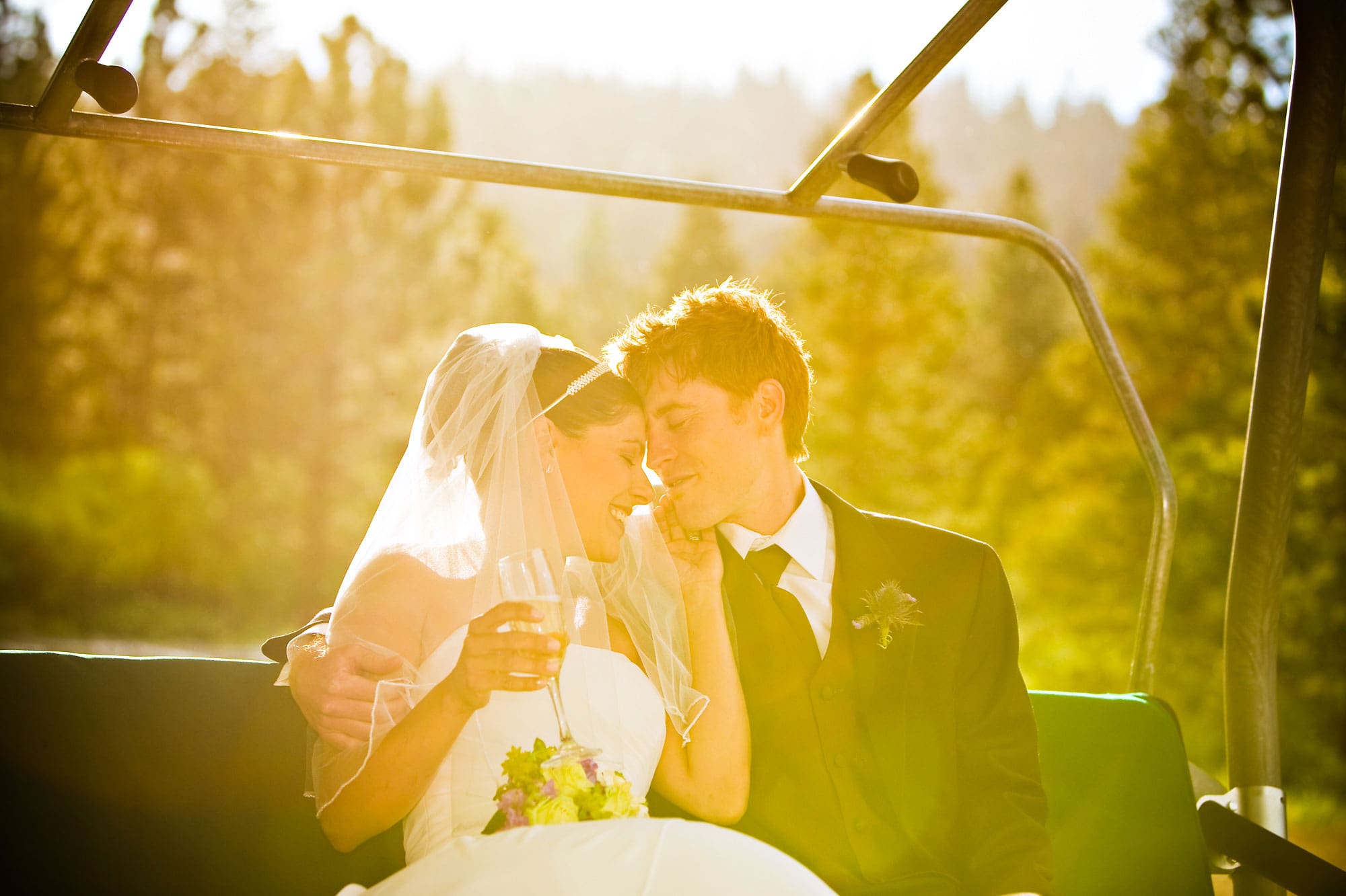 A wedding couple kissing on ski chair.