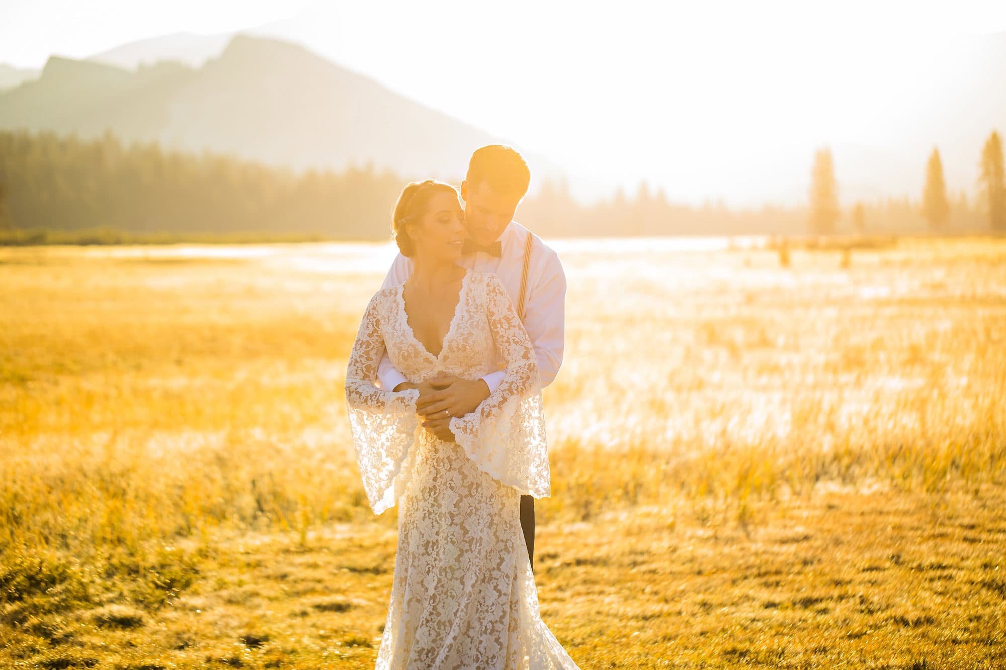 Wedding couple in golden light on the edge of an alpine meadow.