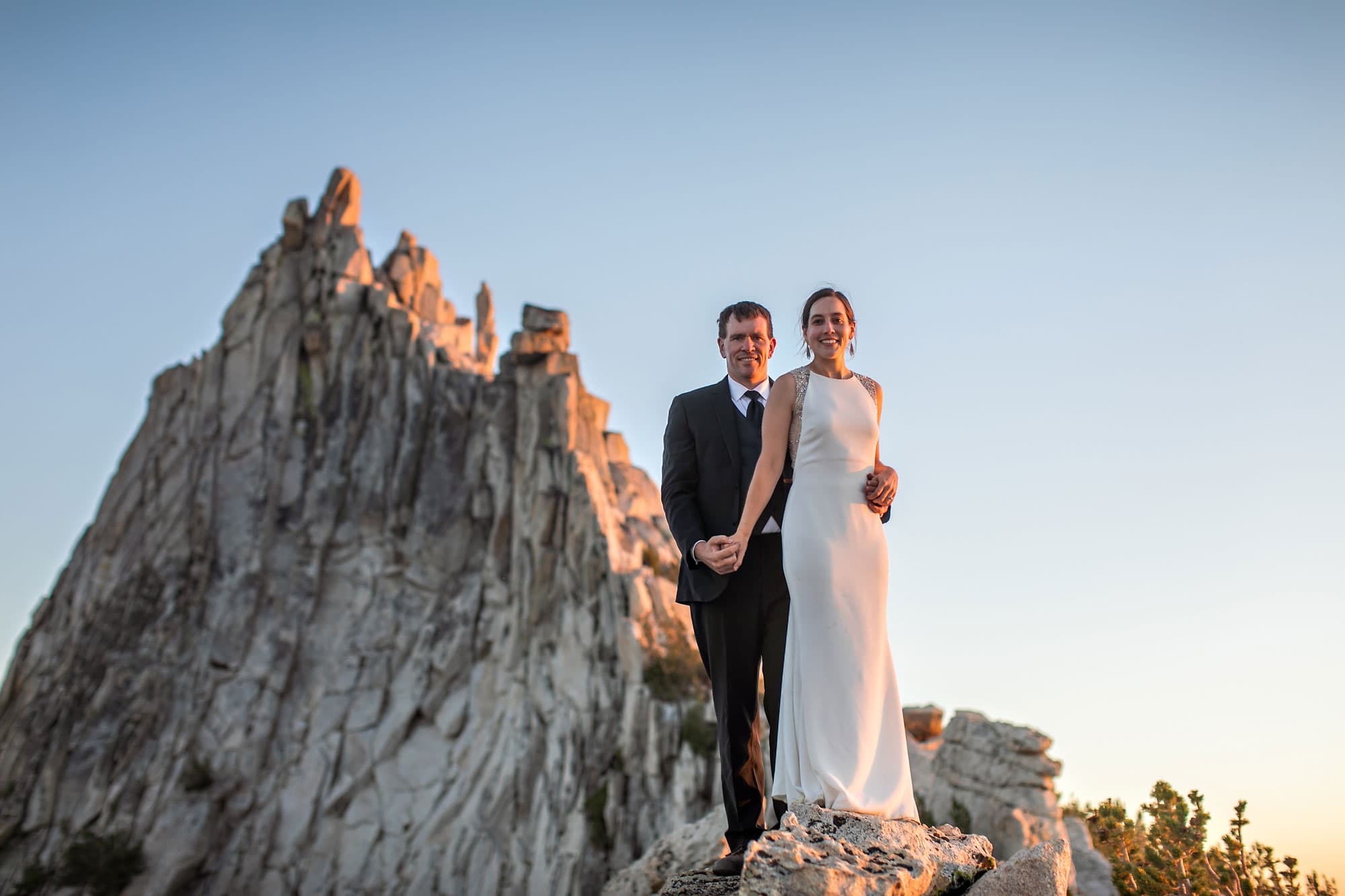 A wedding couple on top of mountain with sunset and moon.