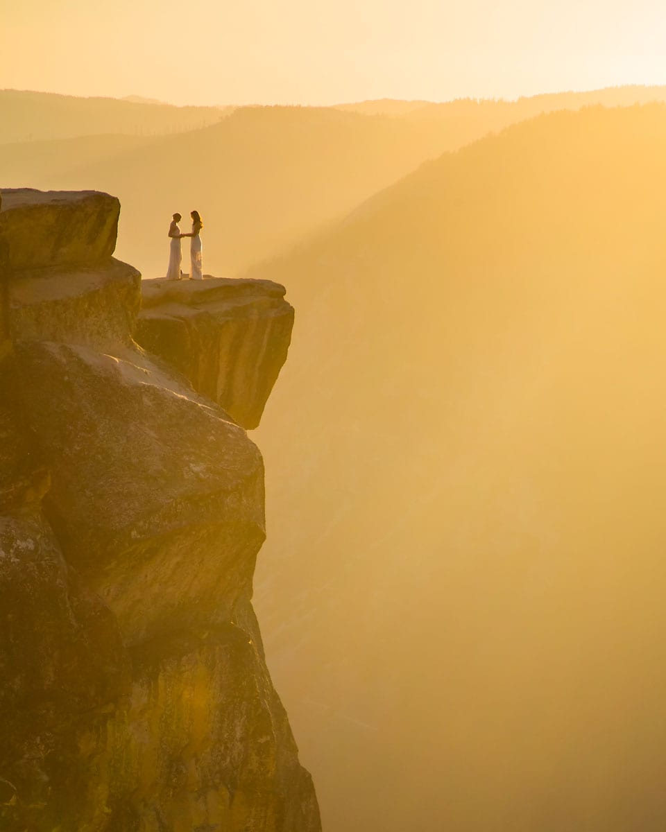 A lesbian wedding couple standing on top of a mountain with magical light
