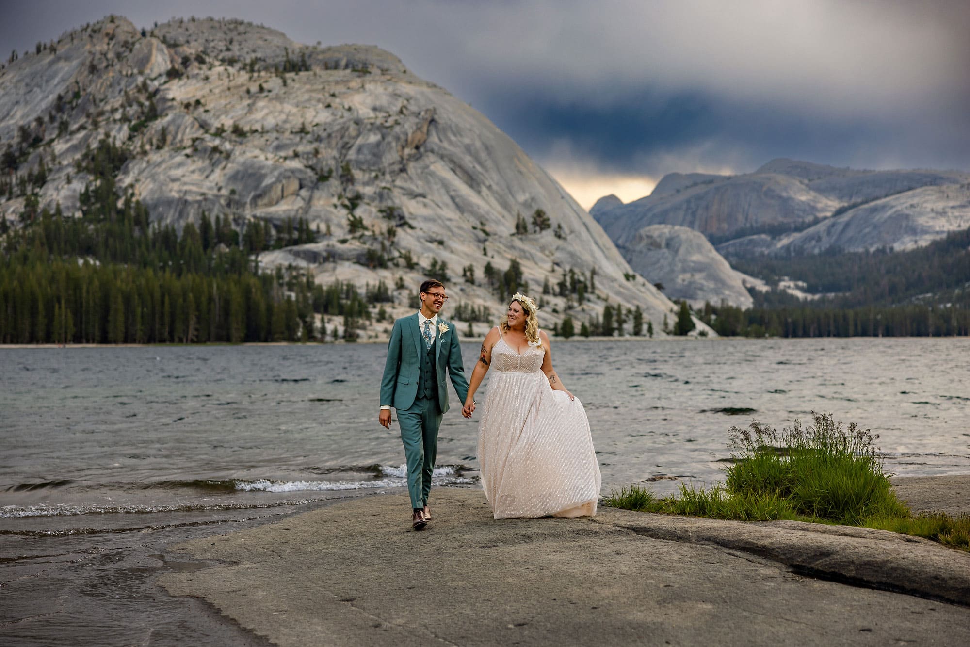 Wedding couple walking along a lakeside with storm clouds.