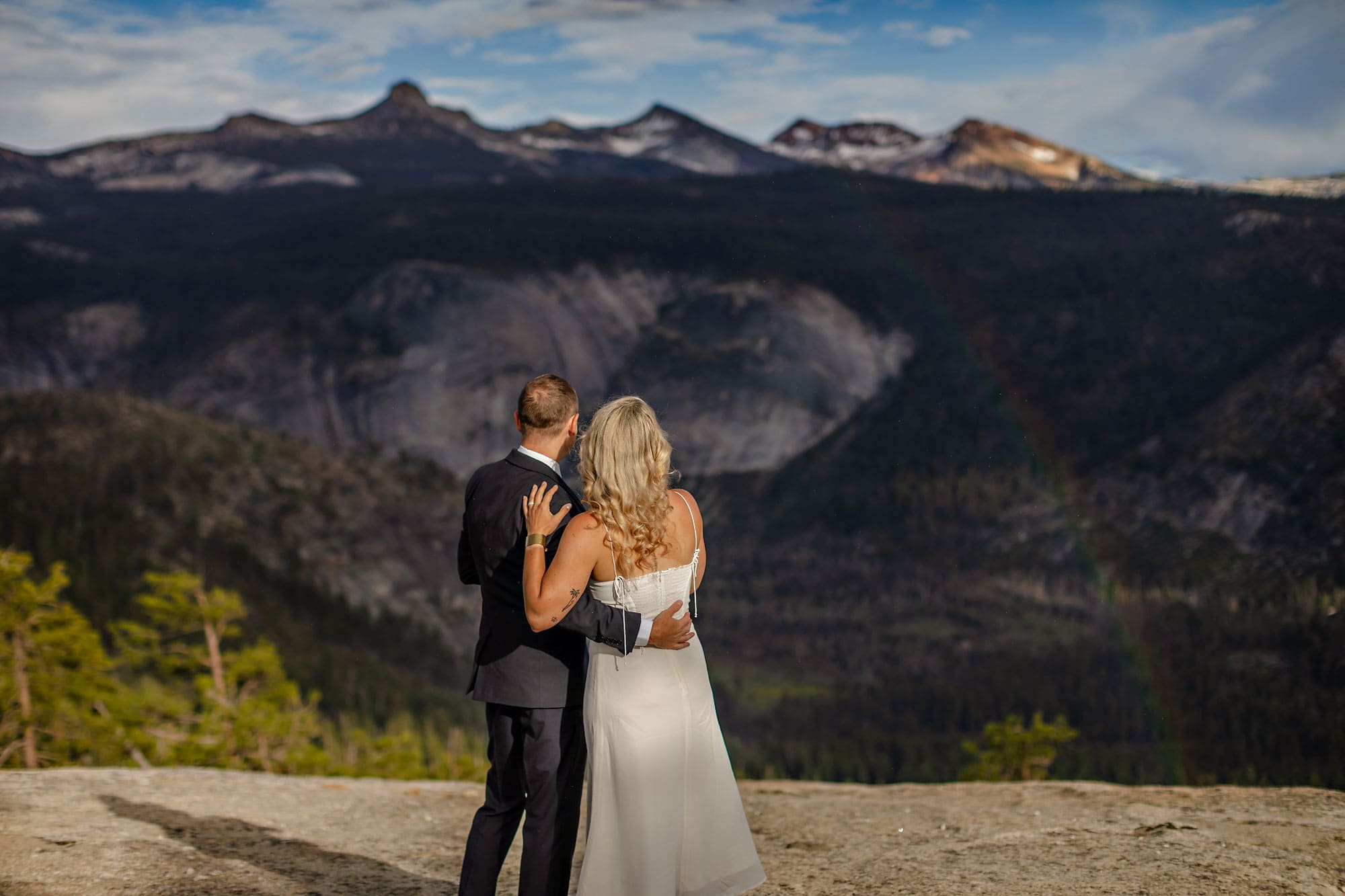 Bride and groom admiring rainbow in distance.