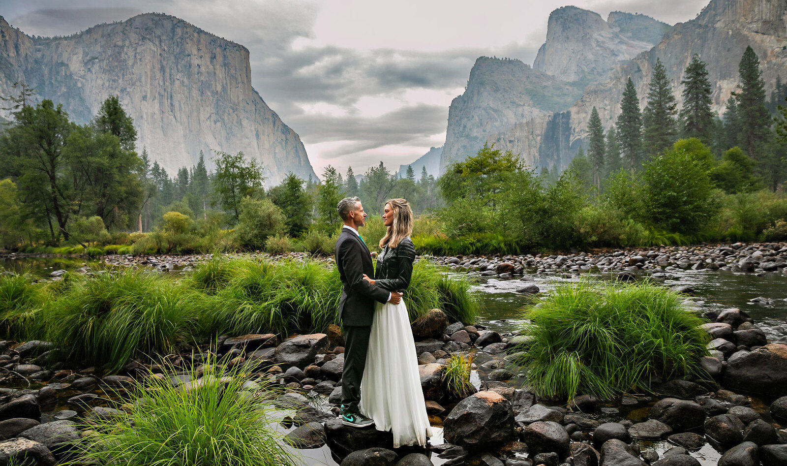 Wedding couple portrait with green foliage next to a river.