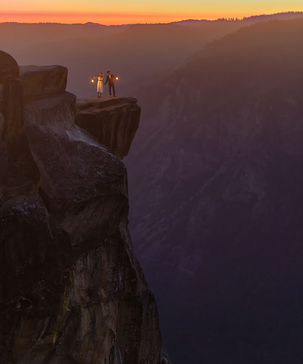 Mixed wedding couple on the edge of a cliff with lanterns during sunset light.