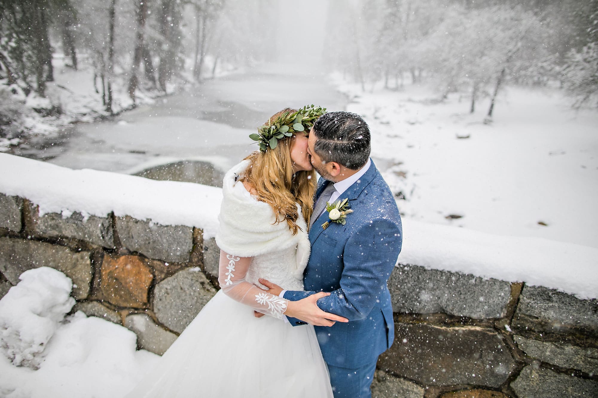 Wedding couple kissing in a snow storm on a bridge.