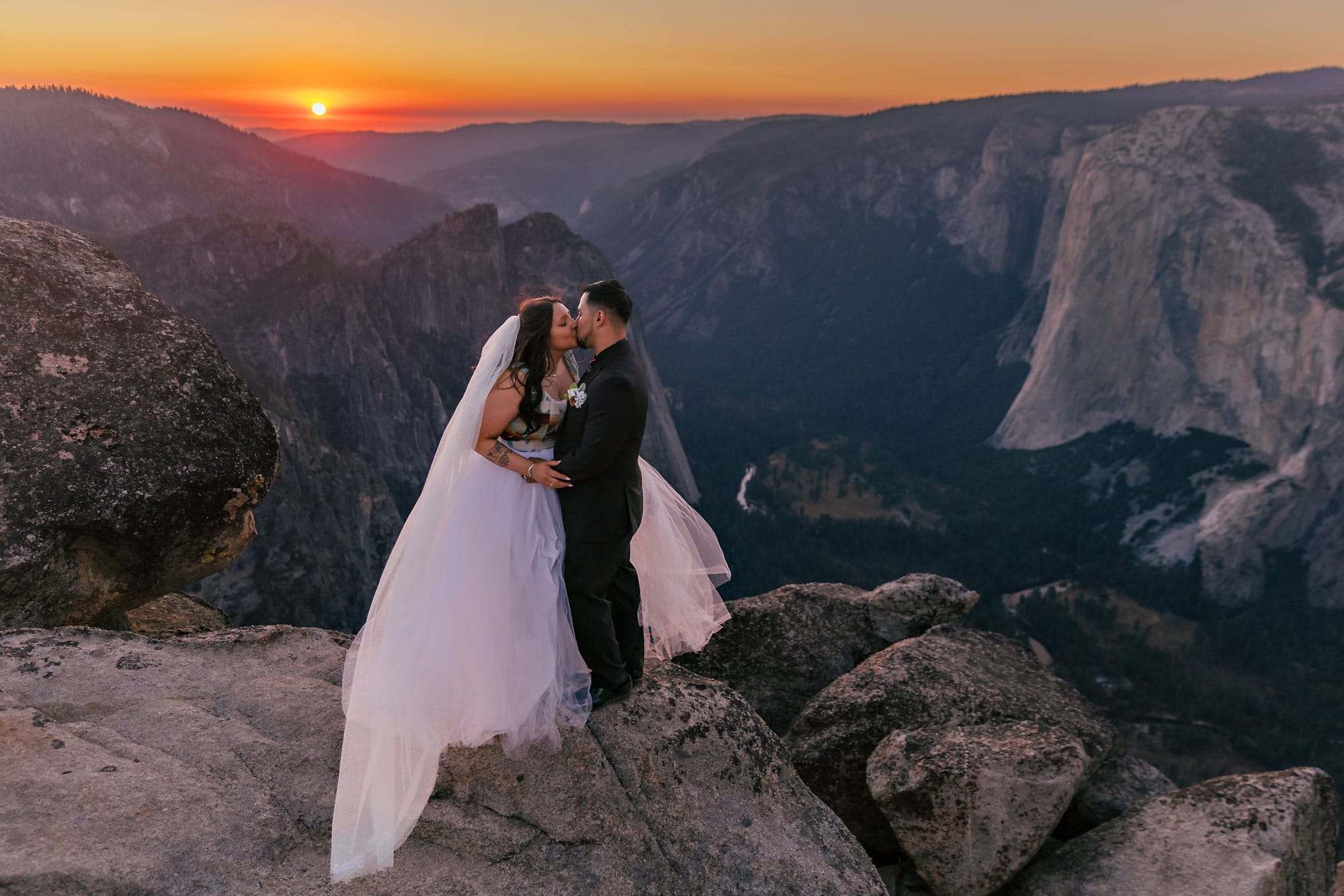 Indigenous mixed wedding couple on the edge of a cliff during sunset light.